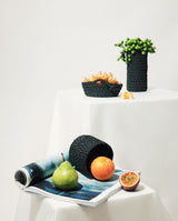 hand-braided black white dots basket lays on the art magazine with green pear and freshly cut passionfruit along side